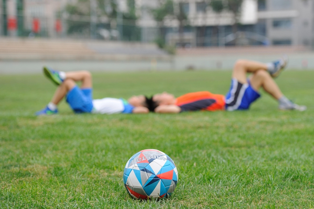 a soccer ball that is multicolored and two boys laying behind resting