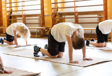 3 students on yoga mats in table top position wearing white tshirts and black shorts