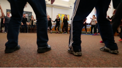 people standing in a circle in a classroom dancing