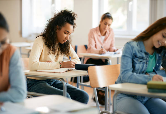 high school students sitting at desks writing notes