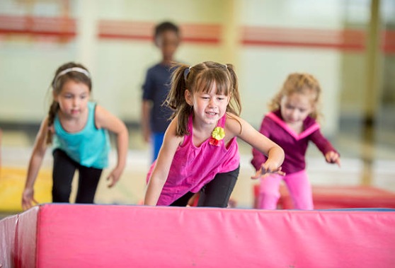 3 young girls running and jumping on a gymnastic mat