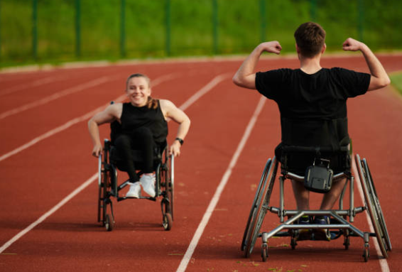 a woman and a man in their late teen years in a wheelchair on a track doing laps