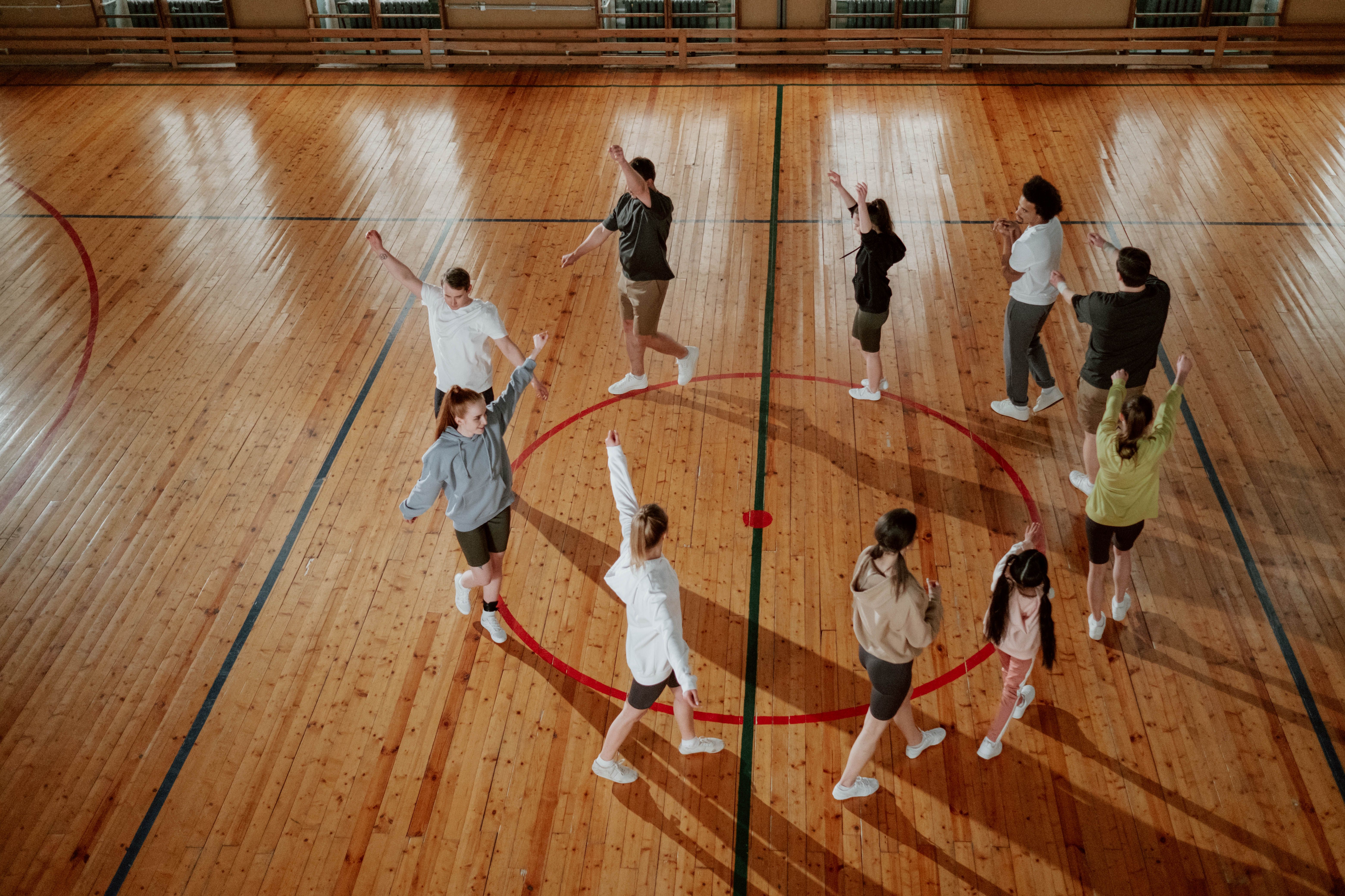 A group of diverse individuals in a gym warming up before practice - Un groupe de personnes d'horizons divers dans une salle de sport, en train de s'échauffer avant l'entraînement