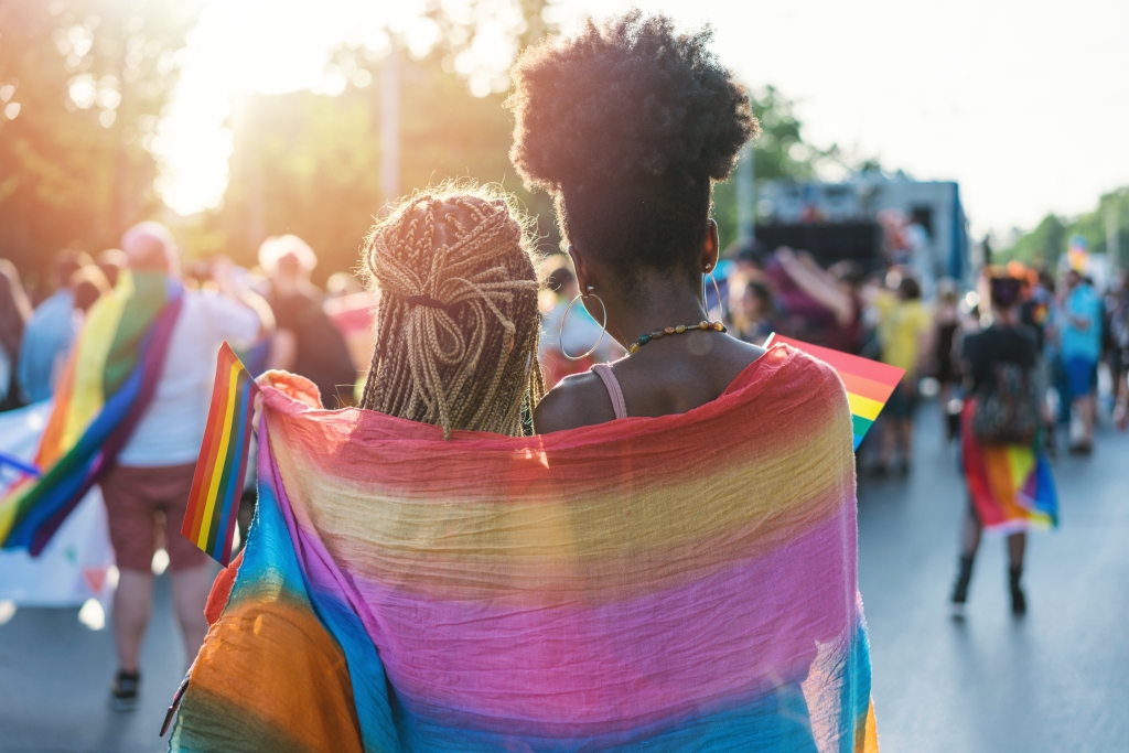 two young people wearing a rainbow flag on their back