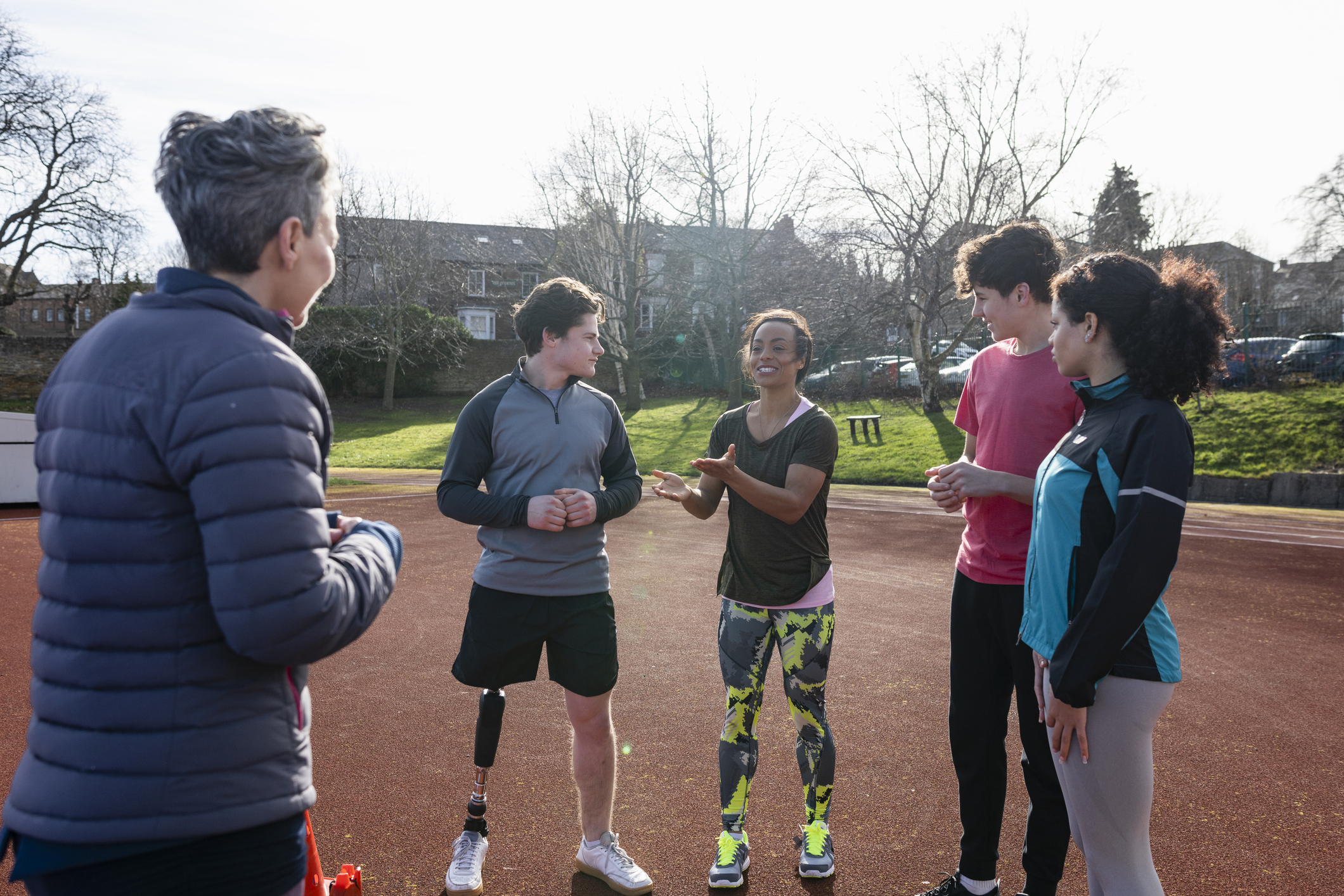 A shot of a diverse young group of athletes sharing a discussion among themselves. One of the male athletes is an amputee with a bionic leg.