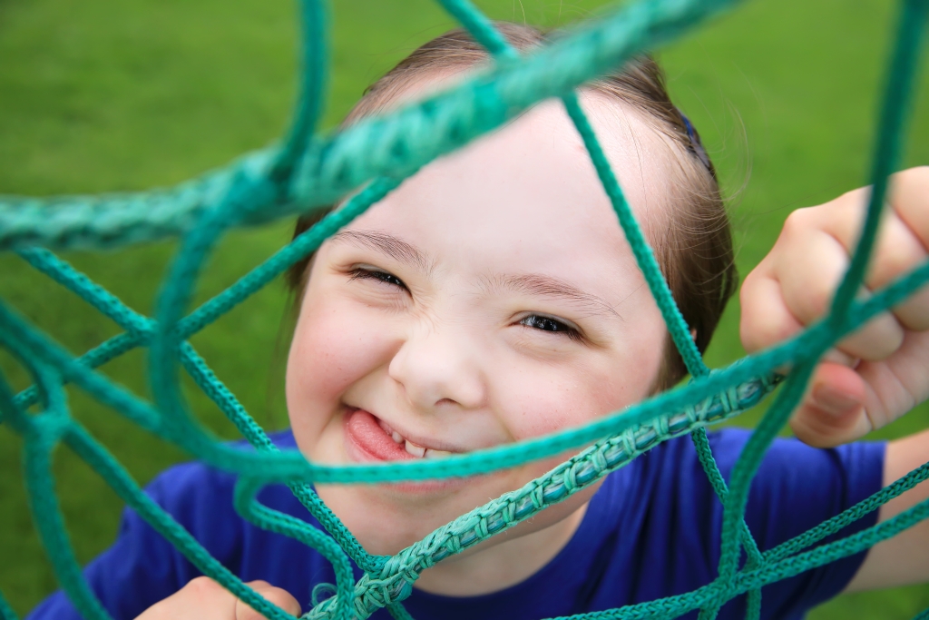 a child behind a green net smiling