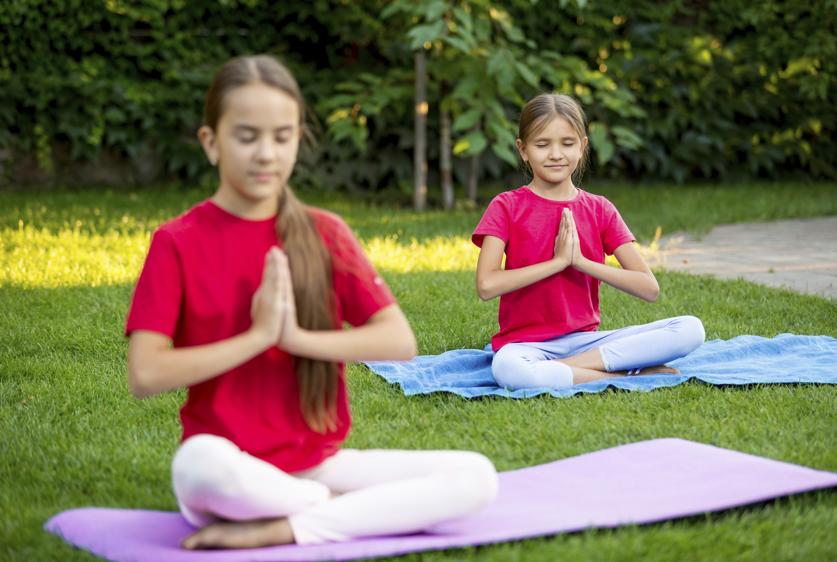 two students sitting on yoga mats in a grass field