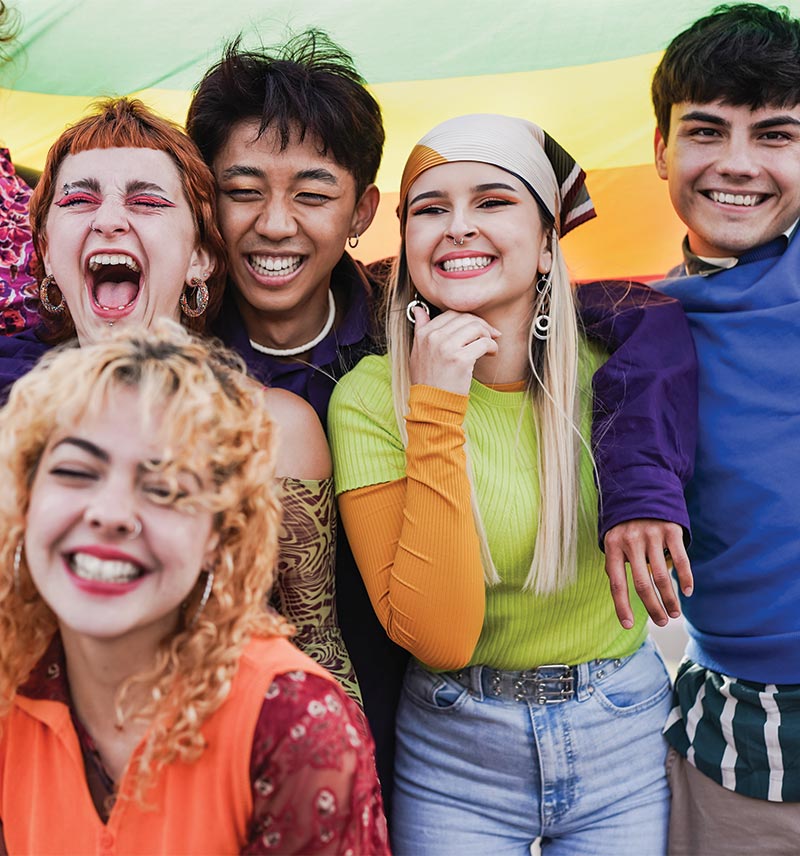 5 teenagers in front of a pride flag smiling