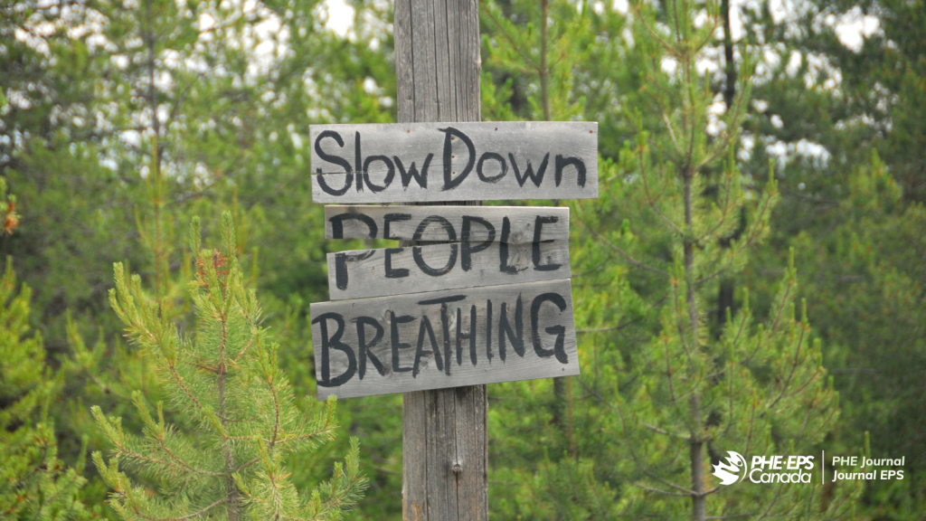 A sign in the forest that says "Slow Down People Breathing"