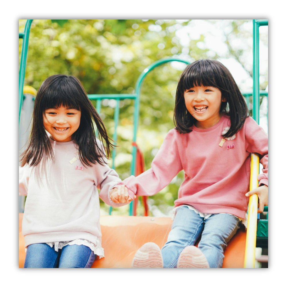 The image shows two young girls playing on top of a playground structure.