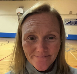 In this photo, Mae is smiling in her school gymnasium.