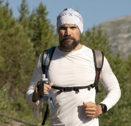 Photo of JJ outdoors wearing a backpack and toque. 
