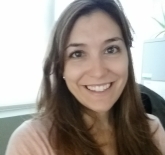 white woman, with long brown hair, wearing a light pink long sleeve shirt