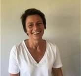 middle aged, woman, with short brown hair, wearing a white v-neck t-shirt