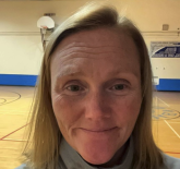 In this photo, Mae is smiling in her school gymnasium.