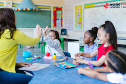 One teacher in front of 4 students. The teacher is high-fiving the left sudent. The 4 students looks happy and are smiling. / Un professeur devant 4 élèves. Le professeur applaudit l'élève de gauche. Les 4 élèves ont l'air heureux et sourient.