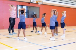 A diverse group of children playing and exercising together in a gymnasium setting.