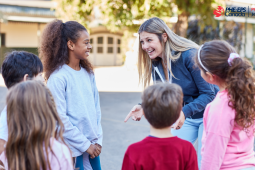 A female teacher talking and smiling with 5 students in front of her / Une enseignante parle et sourit avec cinq élèves devant elle.