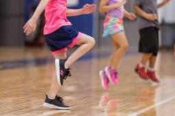 3 young children running on the spot in a gymnasium