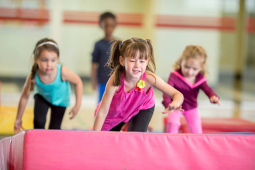 3 young girls running and jumping on a gymnastic mat