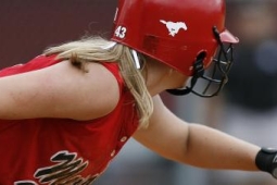a girl with blond hair playing baseball - she is wearing a red helmet, red tank jersey and black and white gloves. 