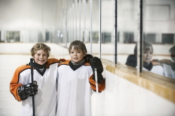 the photo shows two young hockey players on a ice rink smiling