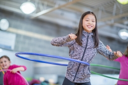 a young girl using a blue hula hoop