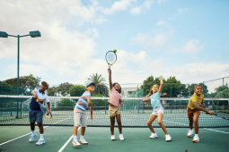 5 children on a tennis court swinging a tennis racket to hit a ball