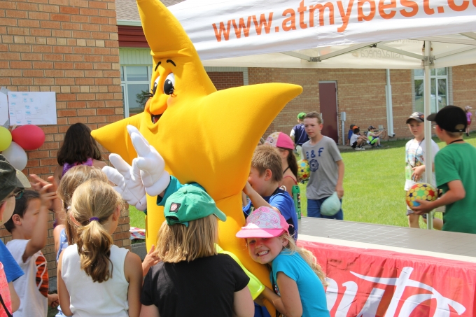At the My Best Play day school event, children surround and embrace Ray the star.