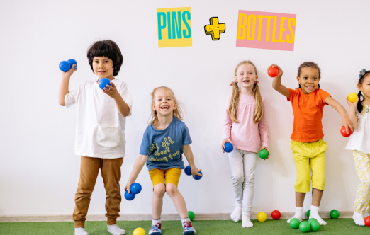 A group of kids are standing against a white wall, smiling and holding colorful balls ready to throw.